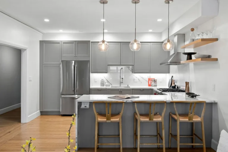 A modern kitchen remodel with a peninsula design, wooden bar stools, and gray cabinets in a San Francisco home.